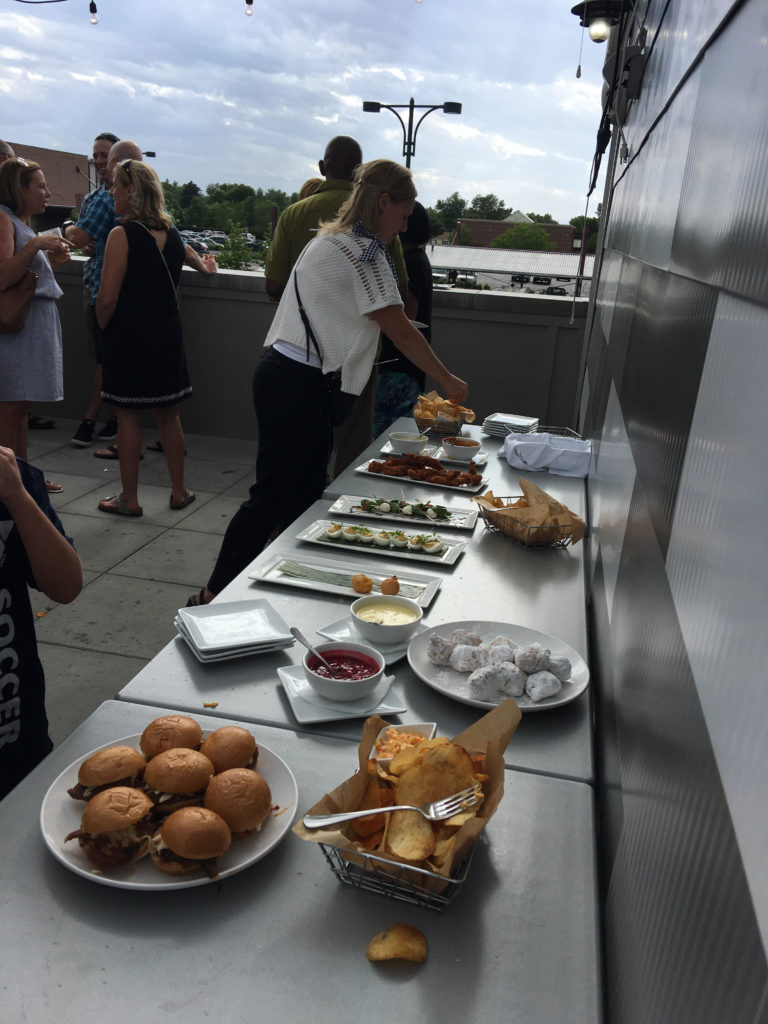 Table of appetizers layed out with woman picking at a dish with food.