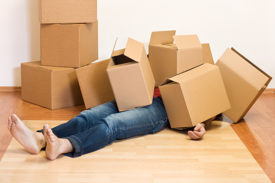 Man laying on wood floor covered in unorganized boxes