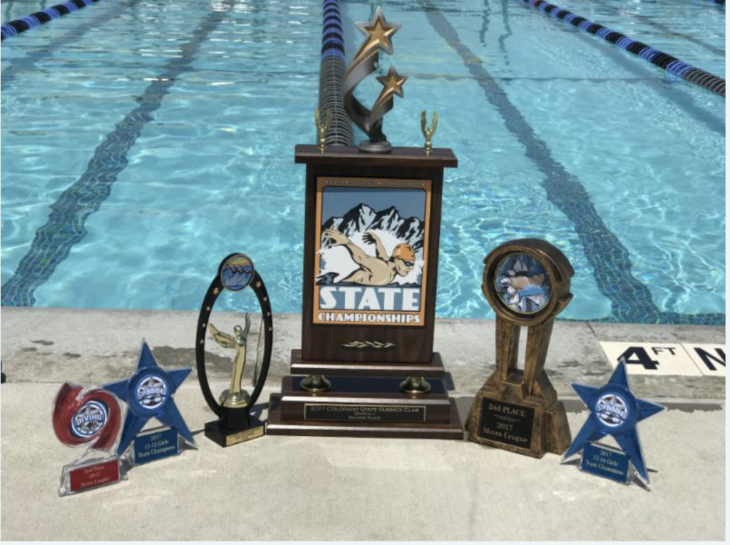 Several swimming trophies with a pool in the background